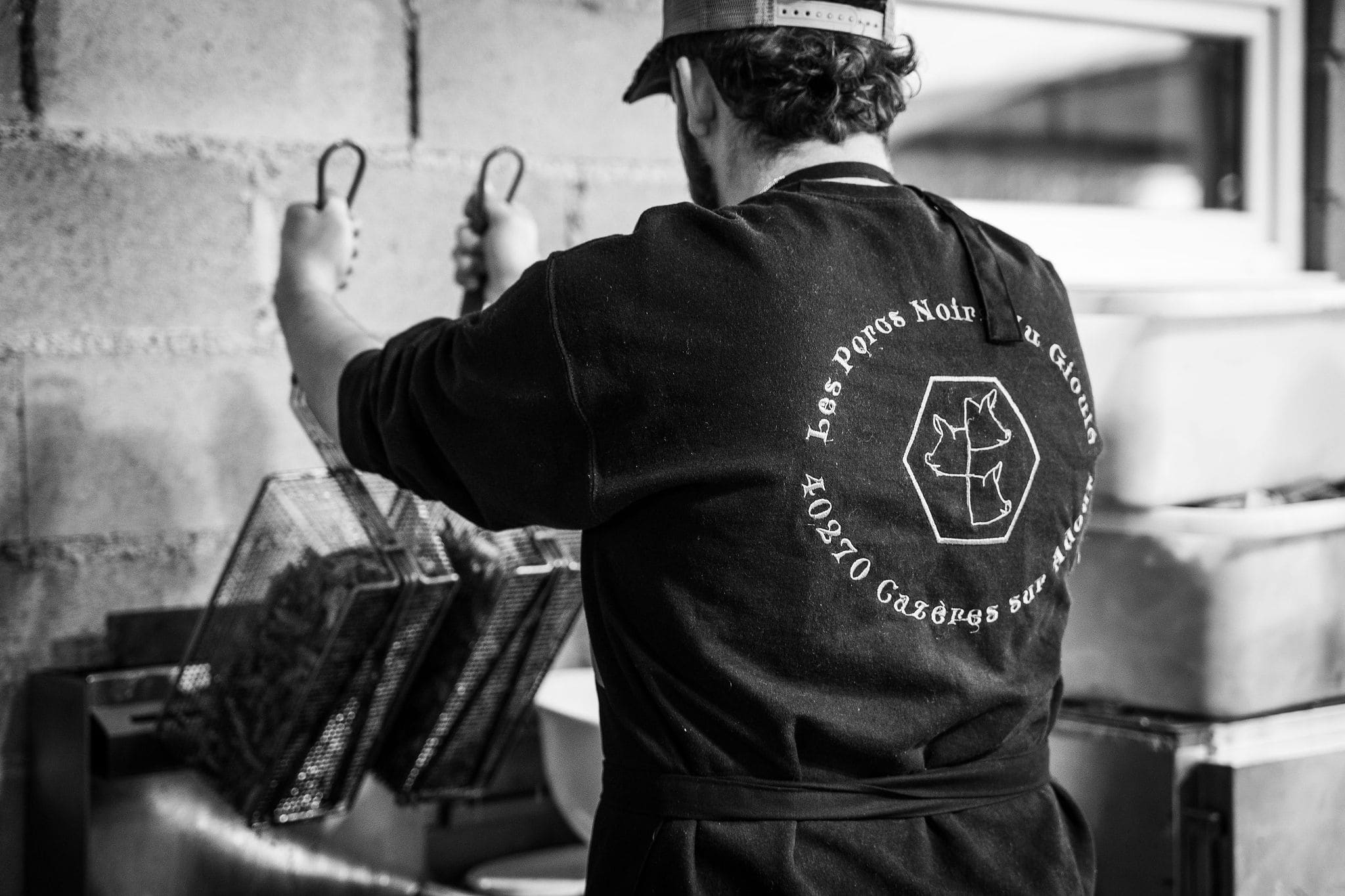 Collaborateur de la Ferme du Gioulé en train de préparer de cuisiner du porc noir